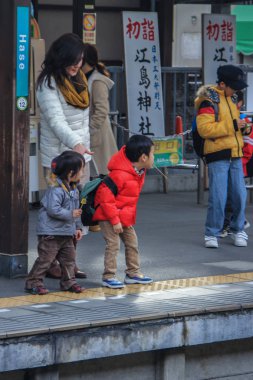 2013.01.06, Kamakura, Japonya. Çocuklar anne ile tren bekliyorsun platformunda.