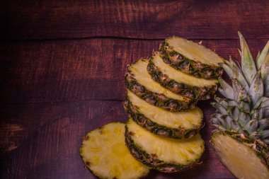 koyu tahta arka planda dilimlenmiş ananas. Mutfak masasında meyve.