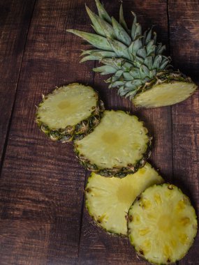koyu tahta arka planda dilimlenmiş ananas. Mutfak masasında meyve.