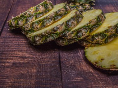 koyu tahta arka planda dilimlenmiş ananas. Mutfak masasında meyve.