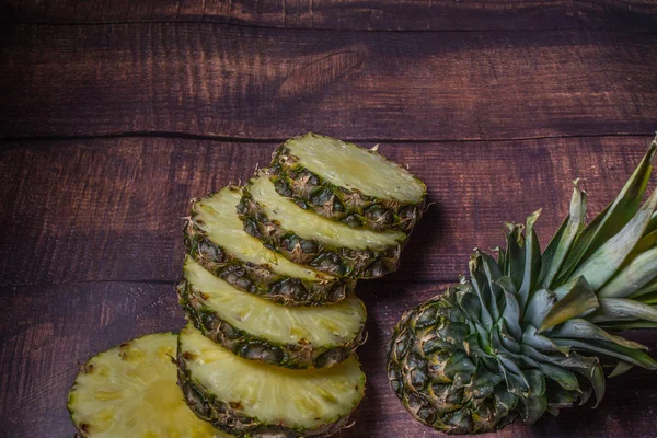 sliced pineapple on a dark board background.  Fruit on the kitchen table.