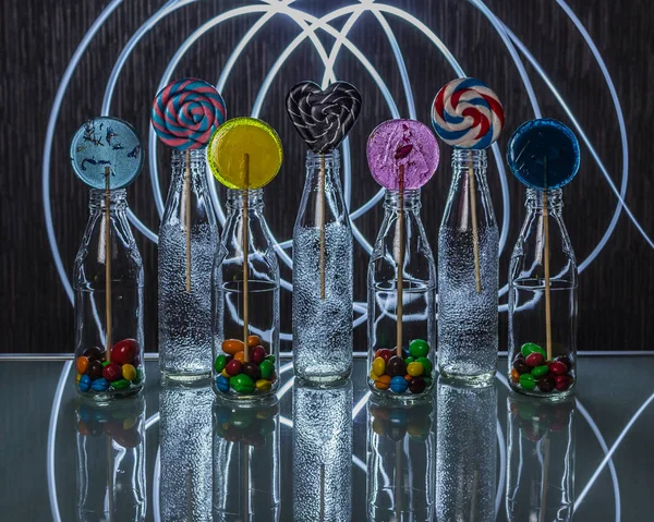 Heldere Kleurrijke Lollipop Snoepjes Flessen Staande Glazen Tafel Het Donker — Stockfoto