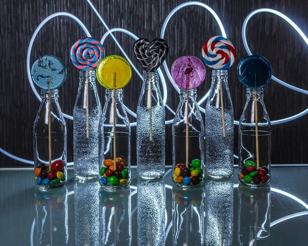 Heldere Kleurrijke Lollipop Snoepjes Flessen Staande Glazen Tafel Het Donker — Stockfoto