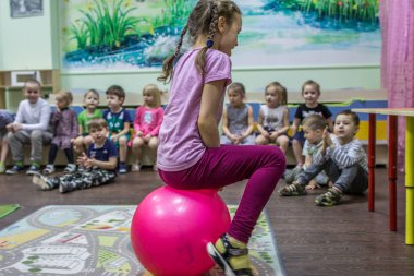 2019.01.22, Moskova, Rusya. Anaokulunda aktif oyunlar oynayan çocuklar. Komik erkek ve kız grubu topa atlama.
