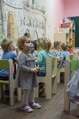 2019.01.22, Moskova, Rusya. Kameraya bakan küçük küçük kız. Anaokulunda yemek yeen çocuklar.