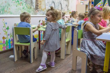 2019.01.22, Moskova, Rusya. Kameraya bakan küçük küçük kız. Anaokulunda yemek yeen çocuklar.