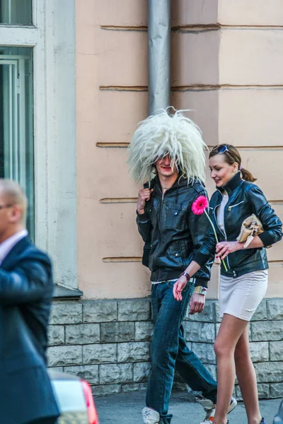 2010.04.11, Moskova, Rusya. Yünlü komik şapka giyen genç bir adam ve sokakta yürüyen genç bir kız.