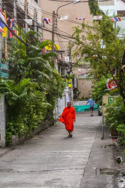 2011.04.30, Bangkok, Tayland. Turuncu cüppe giyen ve dar sokakta yürüyen Budist keşiş.