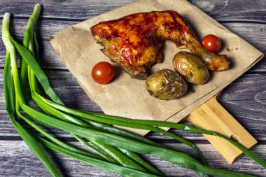 Izgara tavuk, patates, domates, salata, yeşil soğan ve taş plaka üzerinde tuz. Ahşap arka planda ızgara gıda. 