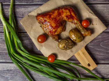 Izgara tavuk, patates, domates, salata, yeşil soğan ve taş plaka üzerinde tuz. Ahşap arka planda ızgara gıda. 