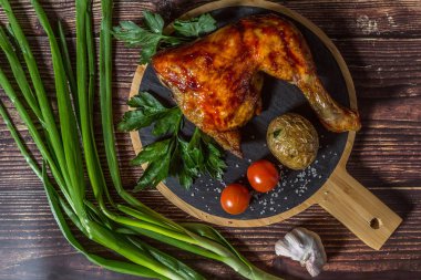 Izgara tavuk, patates, domates, salata, yeşil soğan ve taş plaka üzerinde tuz. Ahşap arka planda ızgara gıda. 