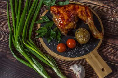 Izgara tavuk, patates, domates, salata, yeşil soğan ve taş plaka üzerinde tuz. Ahşap arka planda ızgara gıda. 