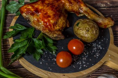 Izgara tavuk, patates, domates, salata, yeşil soğan ve taş plaka üzerinde tuz. Ahşap arka planda ızgara gıda. 