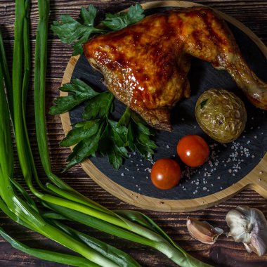 Izgara tavuk, patates, domates, salata, yeşil soğan ve taş plaka üzerinde tuz. Ahşap arka planda ızgara gıda. 