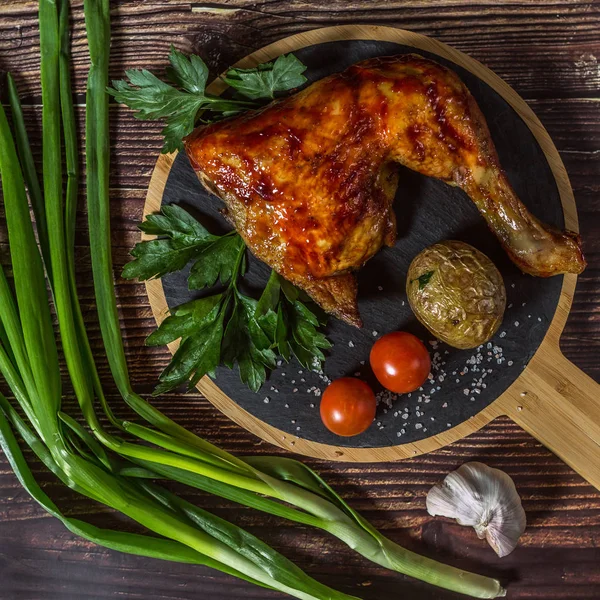 Izgara tavuk, patates, domates, salata, yeşil soğan ve taş plaka üzerinde tuz. Ahşap arka planda ızgara gıda. 