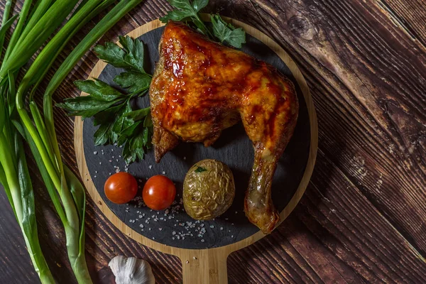 Izgara tavuk, patates, domates, salata, yeşil soğan ve taş plaka üzerinde tuz. Ahşap arka planda ızgara gıda. 