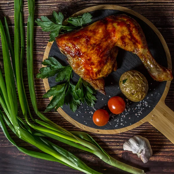 Izgara tavuk, patates, domates, salata, yeşil soğan ve taş plaka üzerinde tuz. Ahşap arka planda ızgara gıda. 