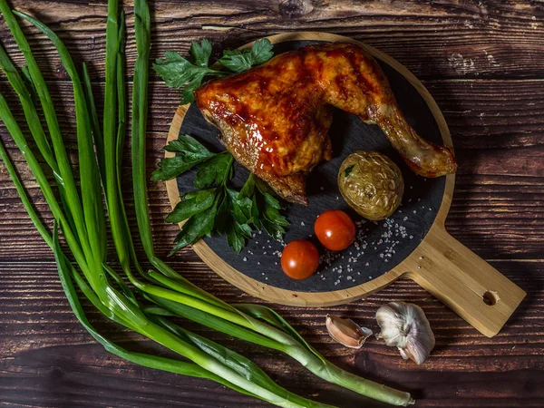 Izgara tavuk, patates, domates, salata, yeşil soğan ve taş plaka üzerinde tuz. Ahşap arka planda ızgara gıda. 