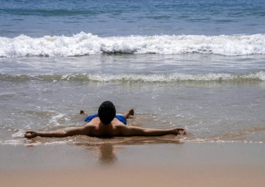 2011.05.02, Phuket, Tayland. Yüzme şortu giyen genç bir adam kollarını açarak sırt üstü yatmış..