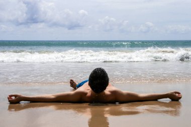 2011.05.02, Phuket, Tayland. Yüzme şortu giyen genç bir adam kollarını açarak sırt üstü yatmış..