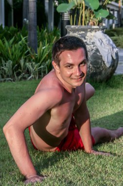 2011.05.06, Phuket, Tayland. Çimlerin üzerinde yatan ve gökyüzüne bakan genç bir adam..