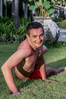 2011.05.06, Phuket, Tayland. Çimlerin üzerinde yatan ve gökyüzüne bakan genç bir adam..