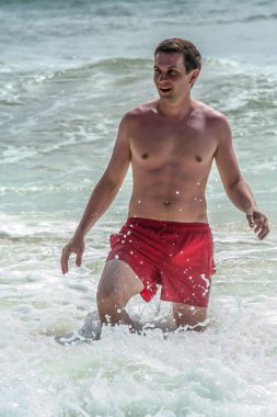 2011.05.06, Phuket, Tayland. Avrupalı turist kırmızı yüzme iç çamaşırı giyiyor ve sahil şeridinde yürüyor. Asya'da seyahat.