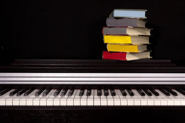 一叠彩色书籍在钢琴上的黑色背景 教育与阅读的概念 — 图库照片