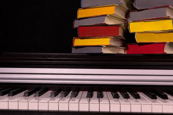 一叠彩色书籍在钢琴上的黑色背景 教育与阅读的概念 — 图库照片