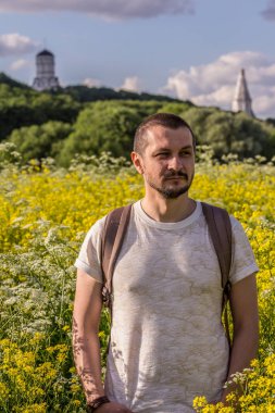 2019.06.01, Moskova, Rusya. Eski bir kilisenin arka planında çiçek açan alanda duran genç bir adam..