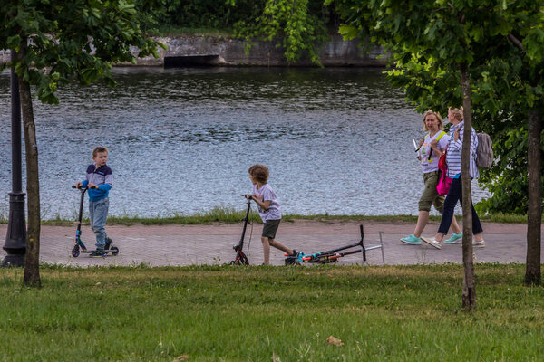 2019.06.01, Moscow, Russia. A boys riding a scooter along the river bank. Active lifestyle of a children.