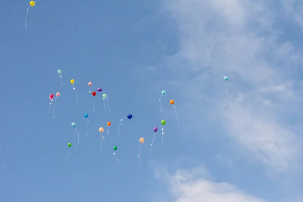 Colorful balloons on background of blue cloudy sky. balloons launched into the sky in honor of the end of the school year.