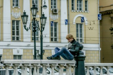 2010.08.22, Moskova, Rusya. Çitin üzerinde oturan ve kitap okuyan bir adam..