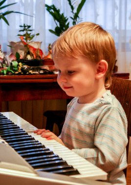 2010.10.03, Maloyaroslavets, Rusya. Piyano çalan küçük sarışın çocuk, yan görünüm. 