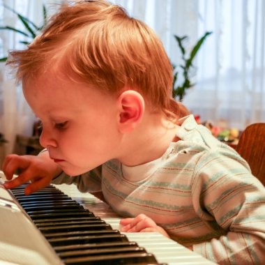 2010.10.03, Maloyaroslavets, Russia. Little blonde boy playing piano, side view.  clipart