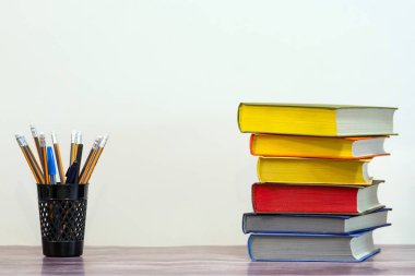 Eğitim kavramı ve okula hazırlık. Beyaz arka plan üzerinde renkli kitap ve kalem yığını.