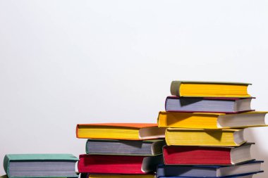 Eğitim kavramı ve okula hazırlık. Beyaz arka planüzerinde renkli kitap yığınları bölünmüş düzeyde. Bilgi bir güçtür.