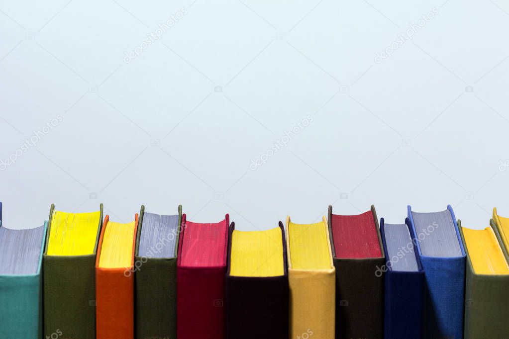 Concept of education and preparation for school. Row of colorful books on the white background. Knowledge is a power.