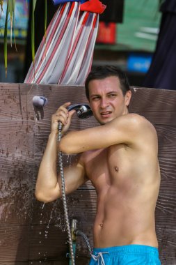 2011.05.08, Phuket, Tayland. Okyanus tuzlu suyundan sonra sahilde duş alan genç bir adam. Asya'da seyahat.