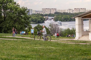 2019.06.02, Moskova, Rusya. Nehrin arka planında tepeye doğru yürüyen bisikletli bir adam. Moskova'da aktif turizm.
