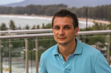 2011.05.10, Phuket, Tayland. Otelin çatısındaki kanepede oturan genç bir adam. Kameraya bakan bir adam. Phuket Turizm.