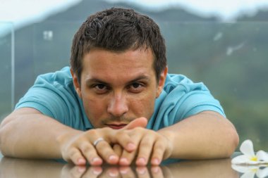 2011.05.10, Phuket, Tayland. Phuket doğanın backgrounf üzerinde cam masa nın yanında oturan genç bir adamın portresi.