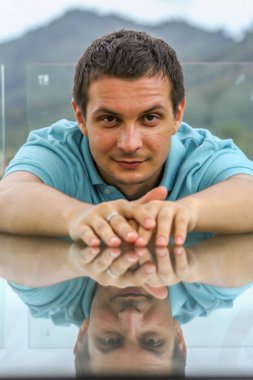 2011.05.10, Phuket, Tayland. Phuket doğanın backgrounf üzerinde cam masa nın yanında oturan genç bir adamın portresi.