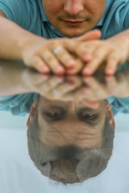 2011.05.10, Phuket, Tayland. Phuket doğanın backgrounf üzerinde cam masa nın yanında oturan genç bir adamın portresi.