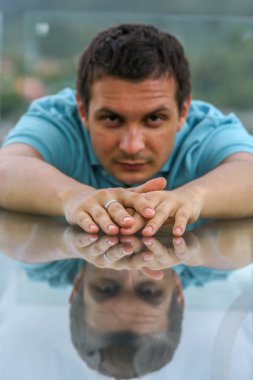 2011.05.10, Phuket, Tayland. Phuket doğanın backgrounf üzerinde cam masa nın yanında oturan genç bir adamın portresi.