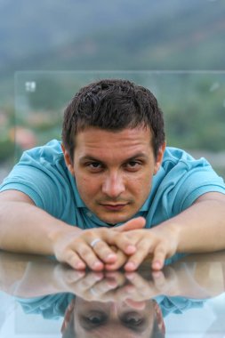 2011.05.10, Phuket, Tayland. Phuket doğanın backgrounf üzerinde cam masa nın yanında oturan genç bir adamın portresi.