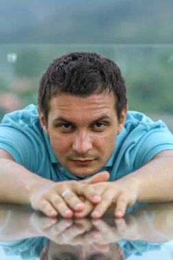 2011.05.10, Phuket, Tayland. Phuket doğanın backgrounf üzerinde cam masa nın yanında oturan genç bir adamın portresi.