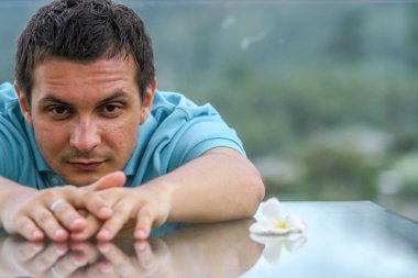 2011.05.10, Phuket, Tayland. Phuket doğanın backgrounf üzerinde cam masa nın yanında oturan genç bir adamın portresi.