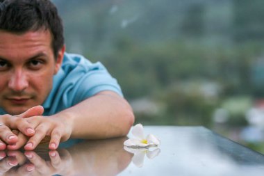 2011.05.10, Phuket, Tayland. Phuket doğanın backgrounf üzerinde cam masa nın yanında oturan genç bir adamın portresi.