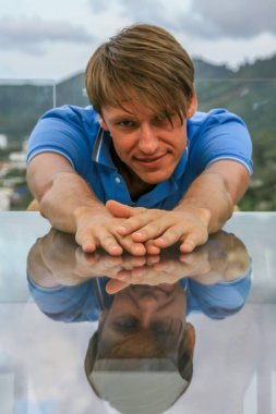 2011.05.10, Phuket, Tayland. Bir masada oturan ve önünde ellerini uzatan genç bir adamın portresi. Asya'da seyahat.